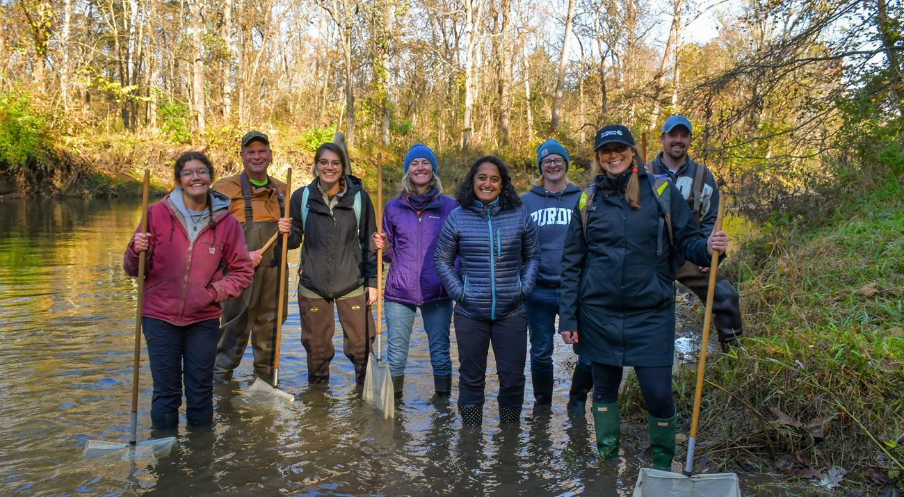 A group of people wading in shallow creek in autumn.