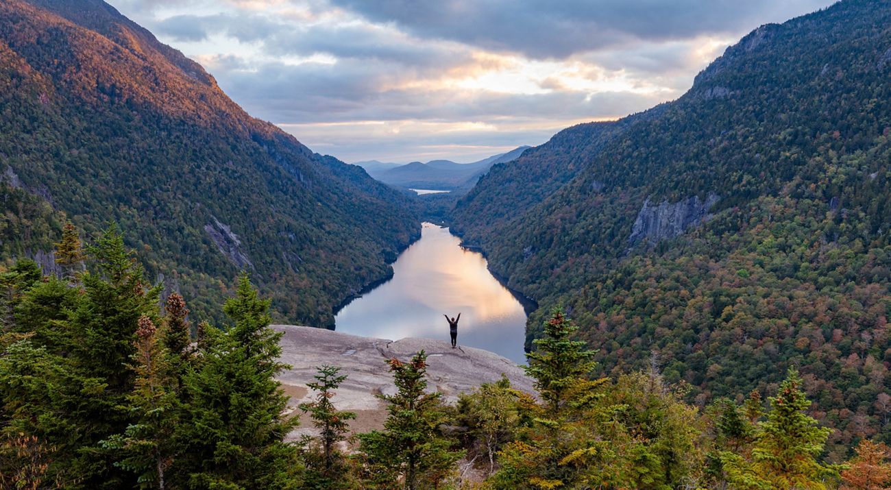 View looking up the length of a dramatic valley with a figure standing on a ledge in the medium distance.