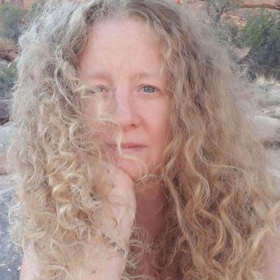 Headshot of poet, Indigo Eriksen, posing with her chin leaning on her hand.