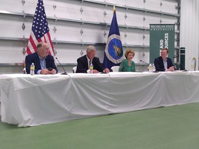 Four panelists sit at a draped table.