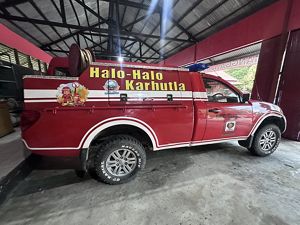 A red fire truck with Indonesian text across it is parked in a garage.