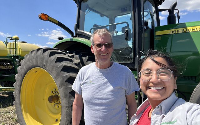 TNC staff member takes selfie with farmer in front of a tractor.