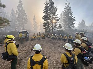A group of people sit in a circle during a prescribed burn. 