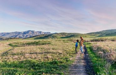 Mom and child hiking on a trail.