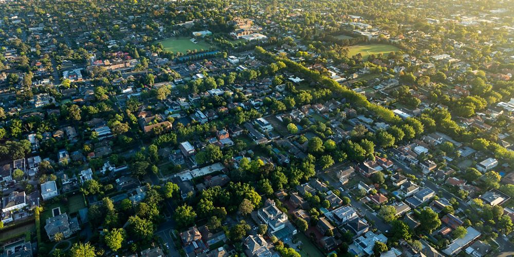 aerial view of suburban neighborhood with houses and buildings and lots of trees throughout