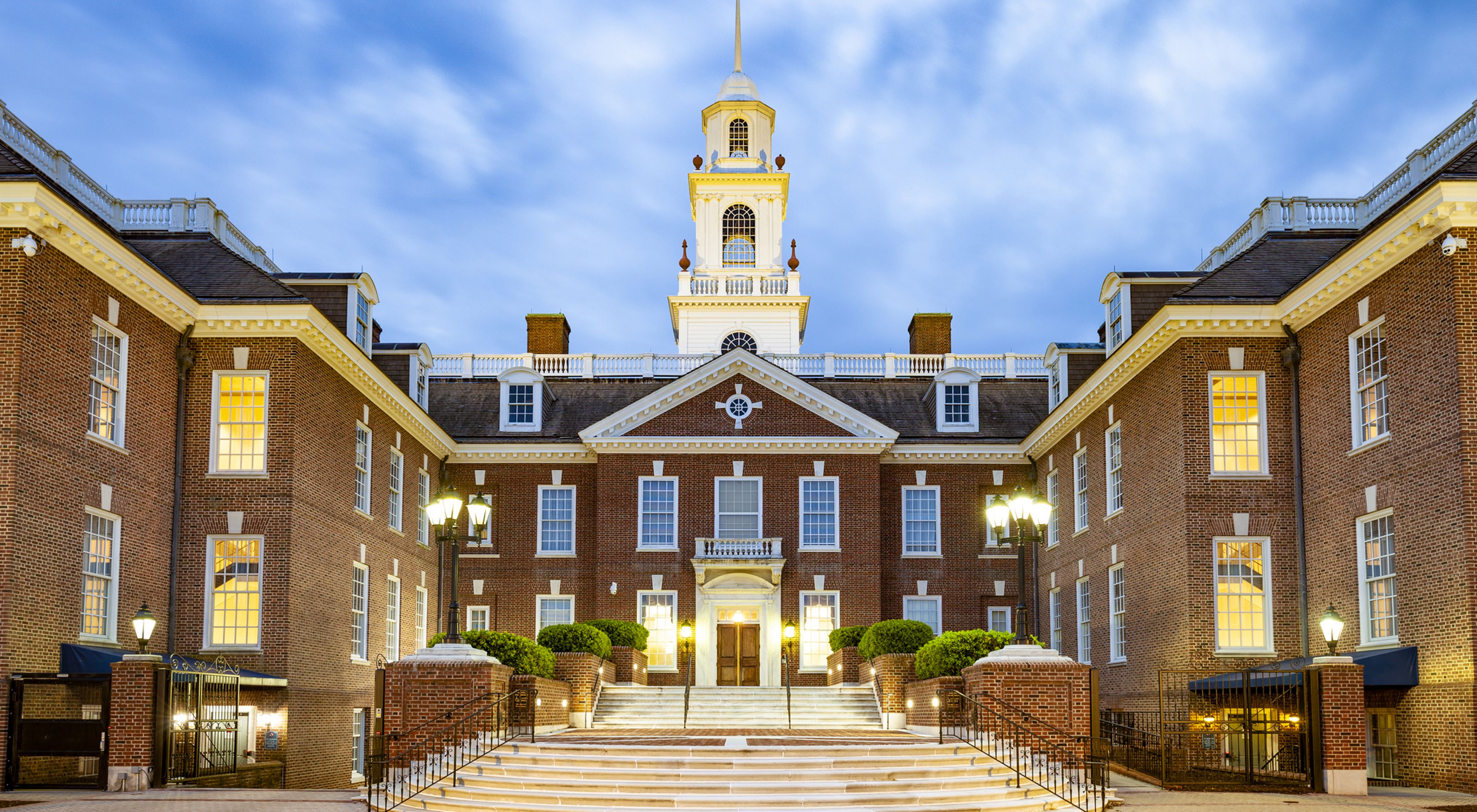 Dramatic view of the Delaware state capitol building. White clouds hang low over the colonial style state house that features a tall spire rising above the front entrance.