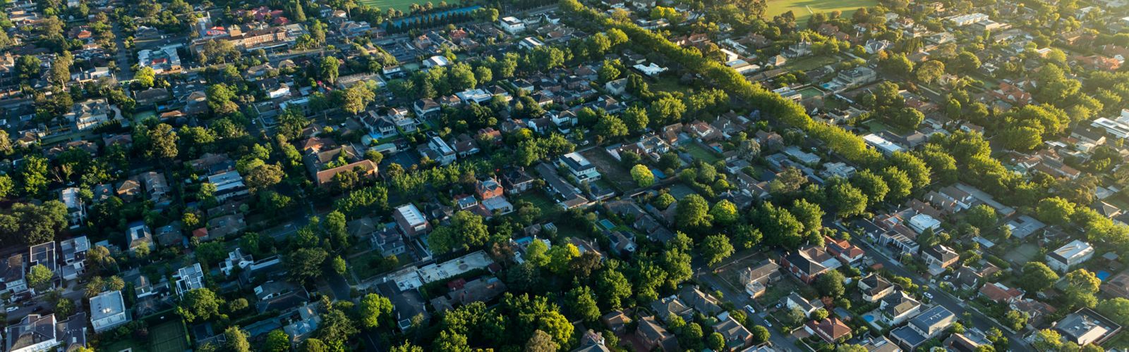 aerial view of suburban neighborhood with houses and buildings and lots of trees throughout