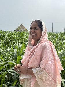 Woman in pink smiles and stands in a field.