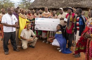 A group of people pose while holding a large check.