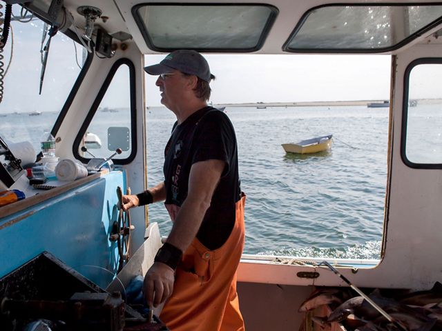 A fisherman on a New England commercial fishing vessel steers the boat.