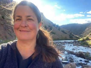 A selfie of a woman with brown hair smiling at the camera.