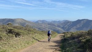 A person wearing a helmet rides a bike through a vast landscape.