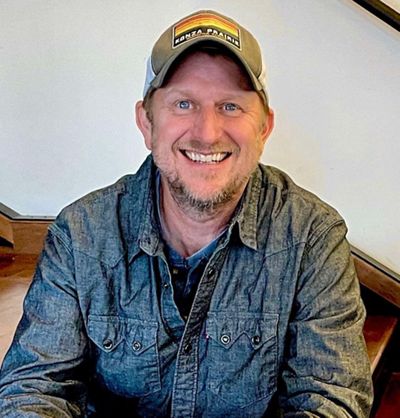 A man wearing a hat smiles for a photo.