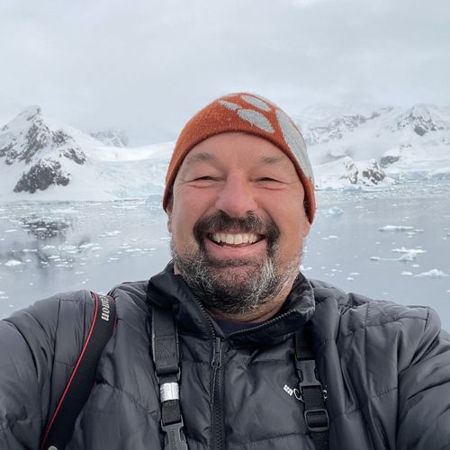 A man in an orange beanie smiles into the camera.