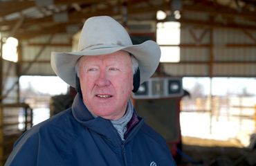 Headshot of John Reed, wearing a white hat and blue jacket.