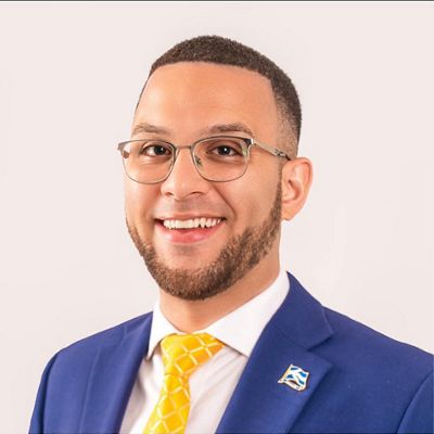 Headshot of Jonathan Guzman in a blue suit jacket and yellow tie.