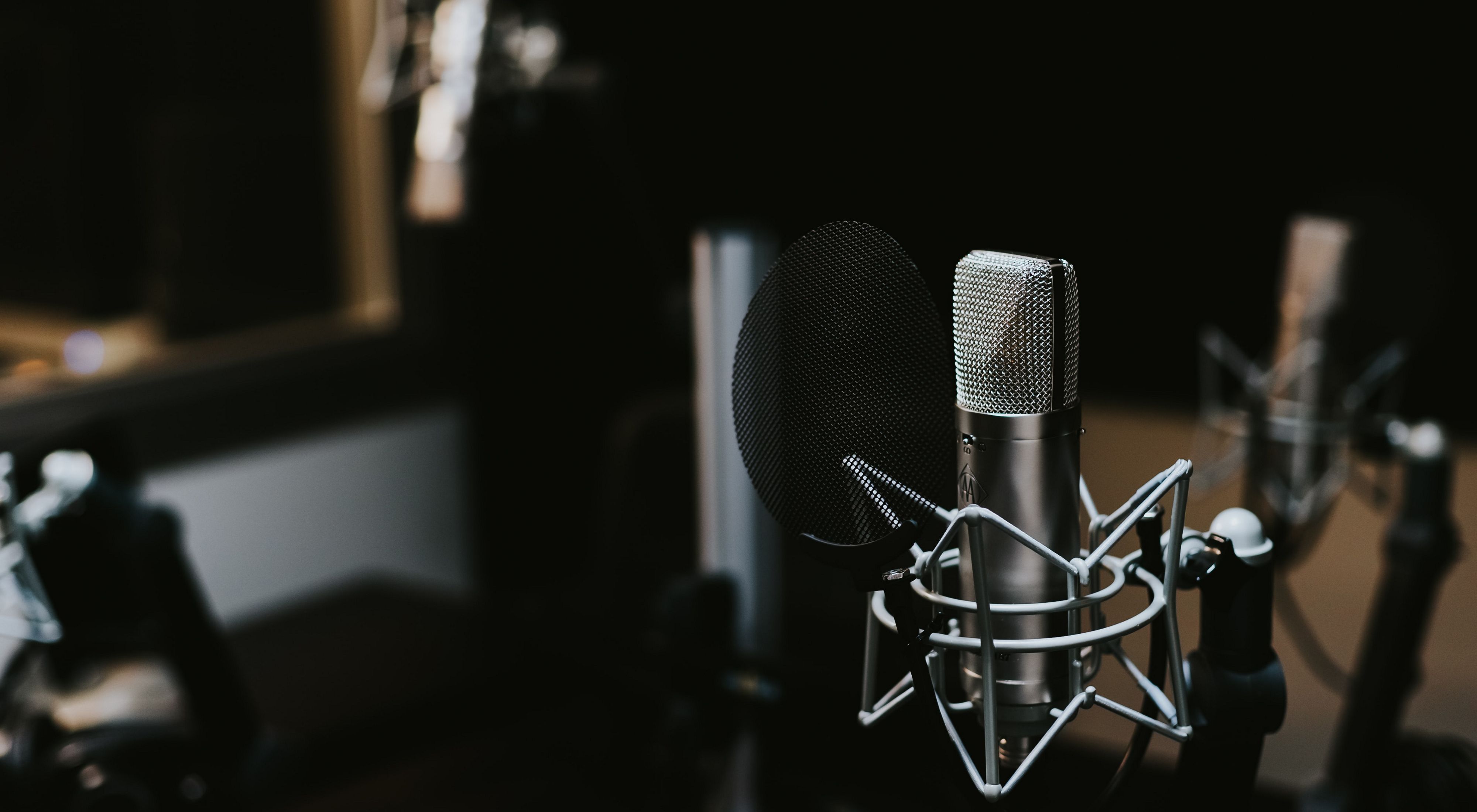 A microphone sits in a dark studio.