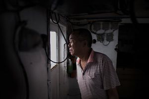 A man looking out a window of a fishing boat.