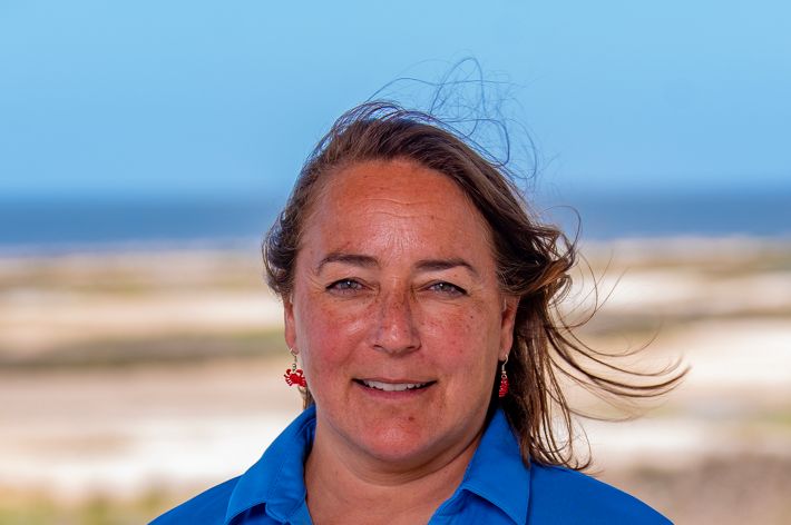 Headshot of Judy Haner in front of a sandy shore.