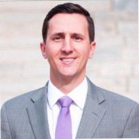 A headshot of a smiling man in a suit. 