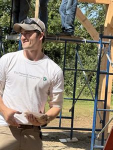 A person wearing a baseball cap looks away from scaffolding.