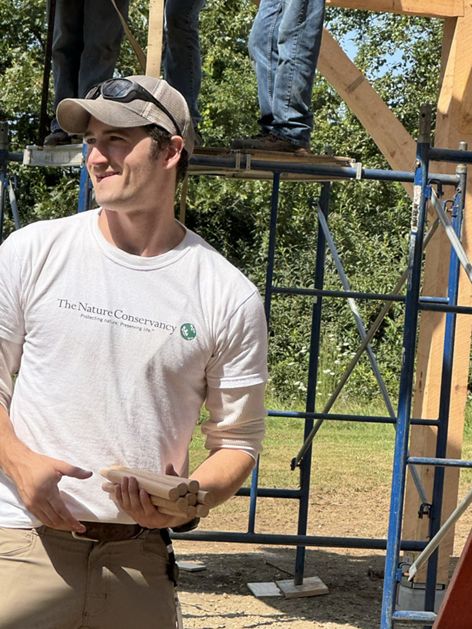 A person wearing a baseball cap looks away from scaffolding.