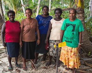 Five women pose for a group shot in a tropical forest.
