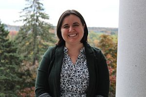 Portrait of Kaitlyn Nuzzo as she smiles toward the camera with the Maine State House behind her.