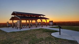The sun sets behind a pavilion surrounded by nature.