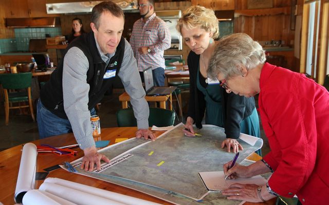 Bill Patterson reviews maps on a table with two women.