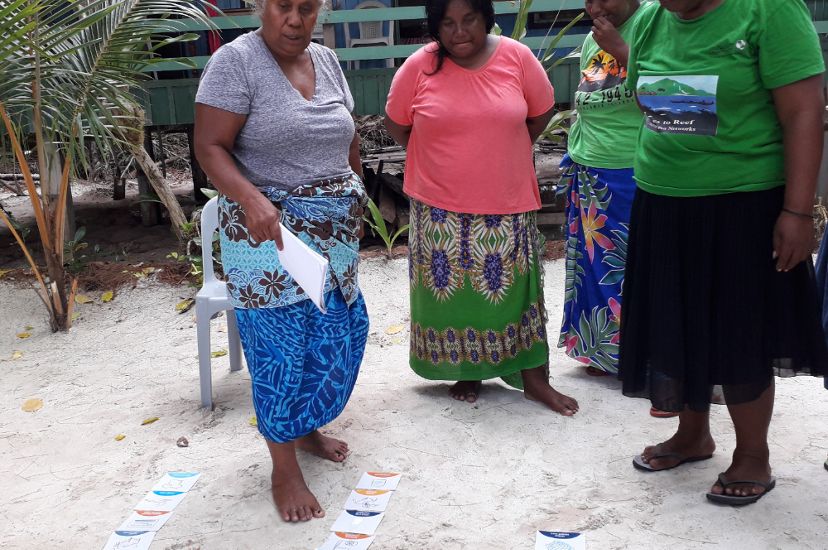 A few women look at cards in the sand during a KAWAKI women's leadership training in 2019.