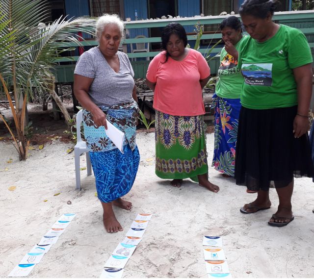 A few women look at cards in the sand during a KAWAKI women's leadership training in 2019.