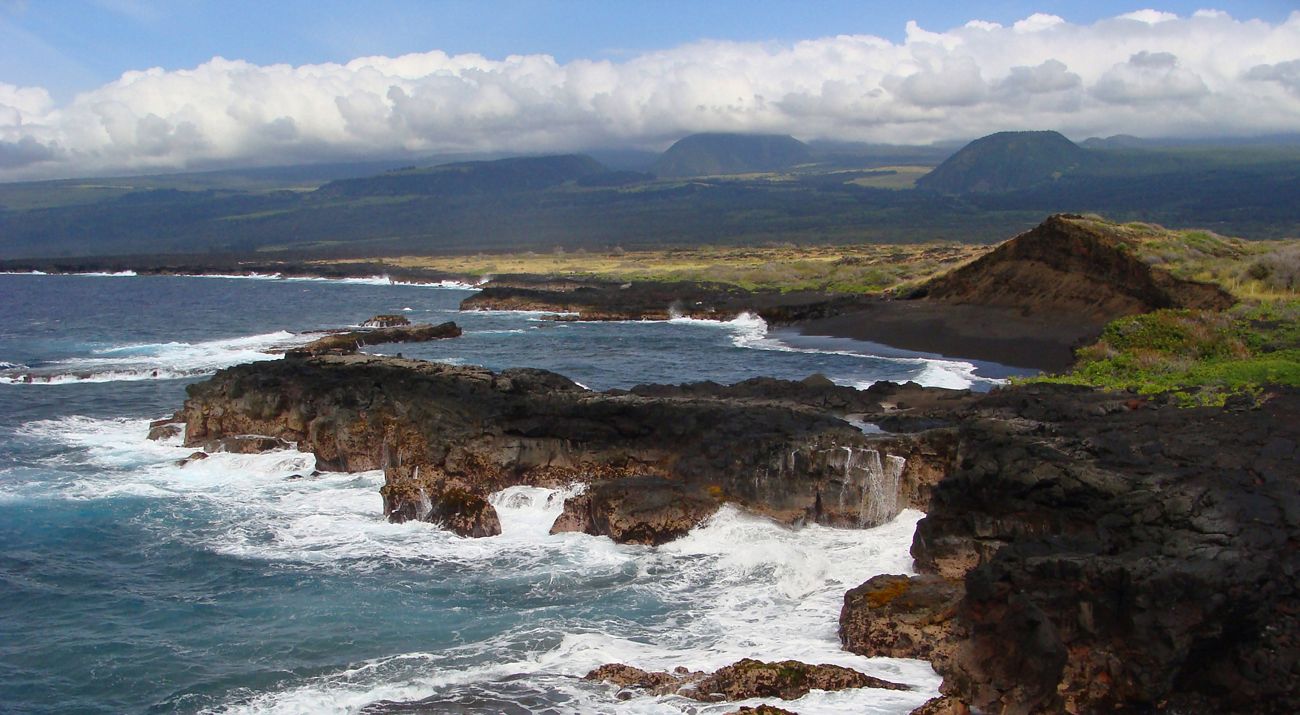 Ocean waves crash up against volcanic rock on the shore at Kamehame Beach.