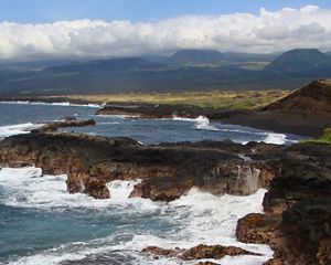 Ocean waves crash up against volcanic rock on the shore at Kamehame Beach.