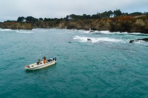 A boat in the water next to a rocky coastline.