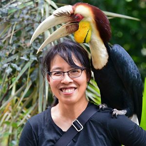 Headshot of Kei Sochi with a wreathed hornbill perched on her shoulder