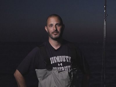 Keith Dunton portrait. He's wearing waders and holding a fishing pole.