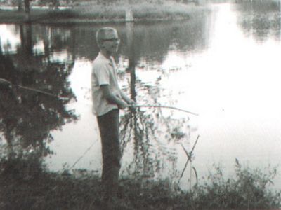 Old photo of a young boy fishing in a pond. 