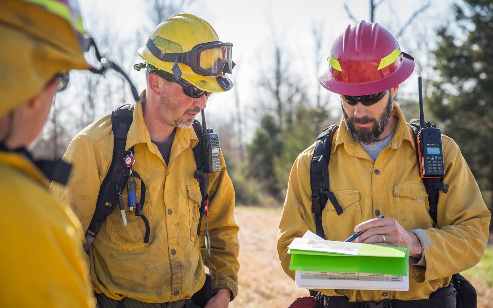 Three members of a fire crew consult a map.