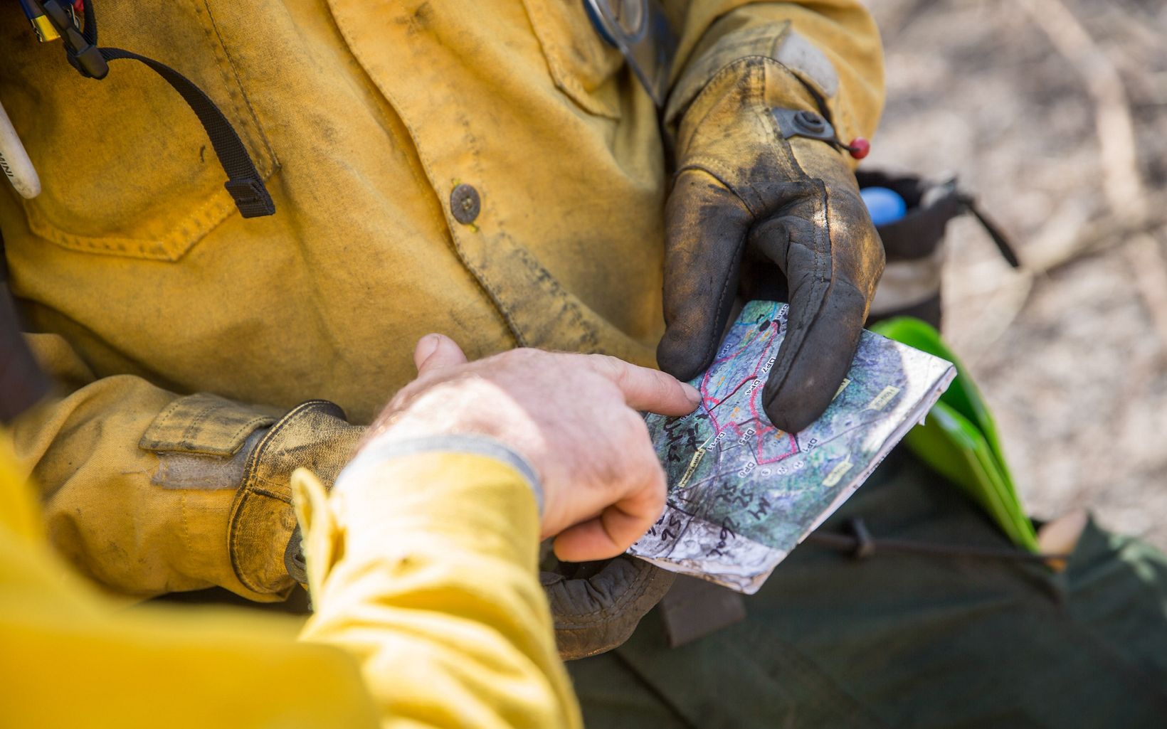 The hands of fire crew members hold a map.