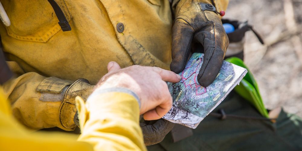 A close-up of two people's hands pointing at a map.