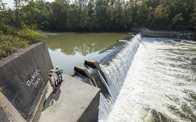 People standing at a large dam in a river.