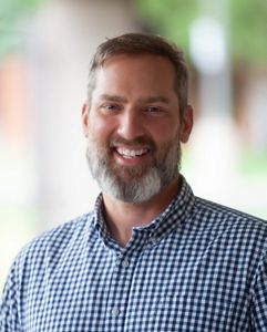 A man is smiling for a headshot.