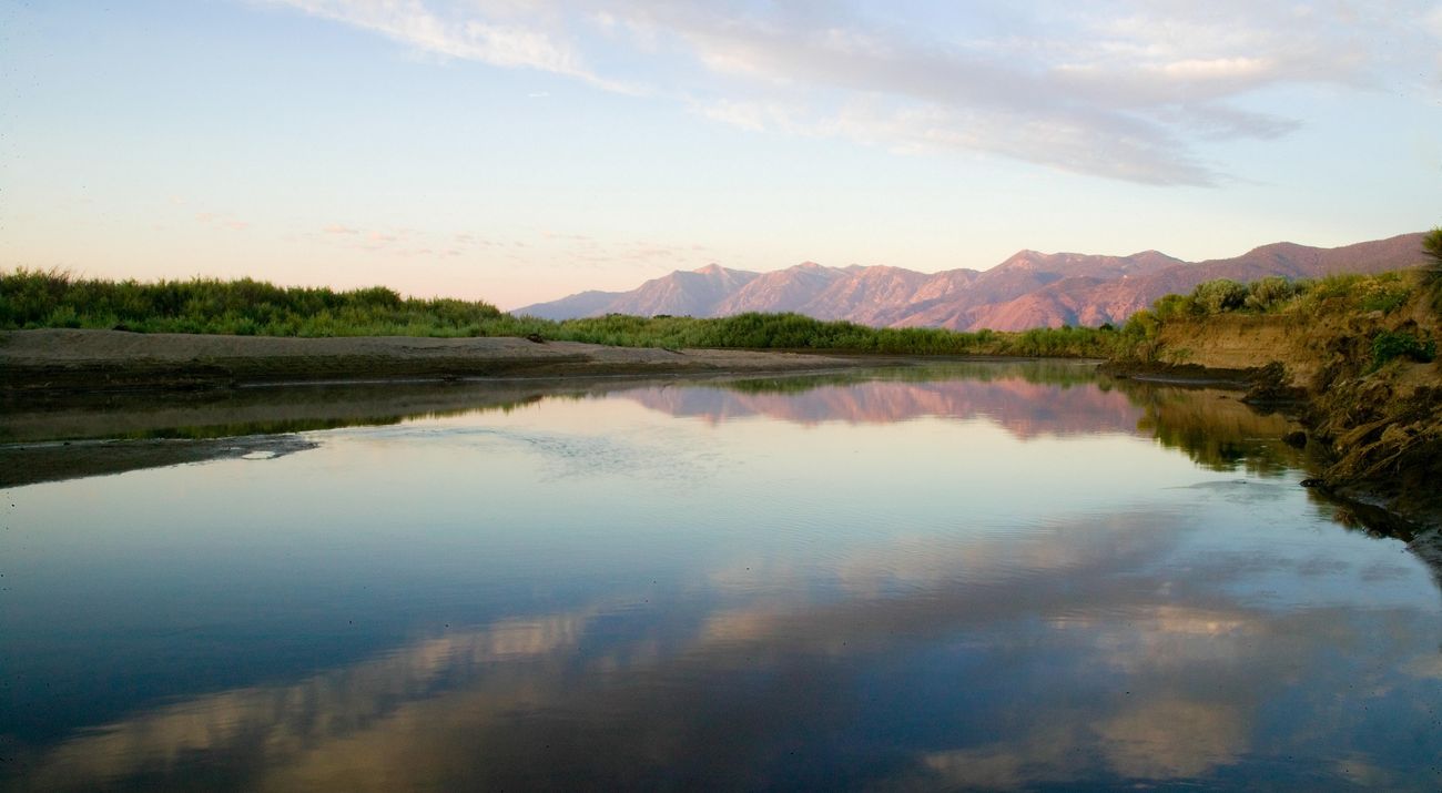 Large river framed by reddish-hued mountains in the background.