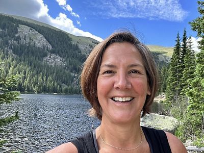 Selfie of Kris Sarri, new state director for TNC in Massachusetts, standing in front of forested mountains in Colorado.