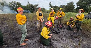 A group of TNC employees huddle together in their bright yellow fire gear during their prescribed burn training. 