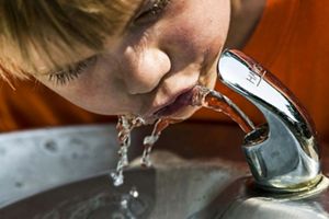 A child drinks from a water fountain.