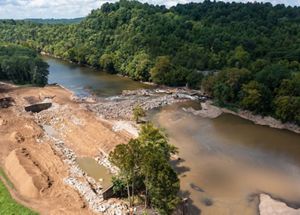 Dam removal underway with heavy machinery employed.