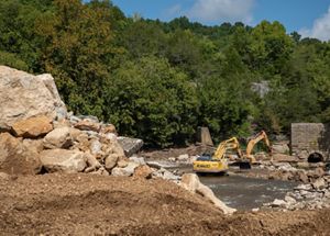 Dam removal with heavy machinery removing broken concrete.