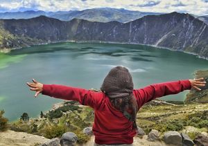 Person spreading arms above Laguna Quilotoa, Ecuador.